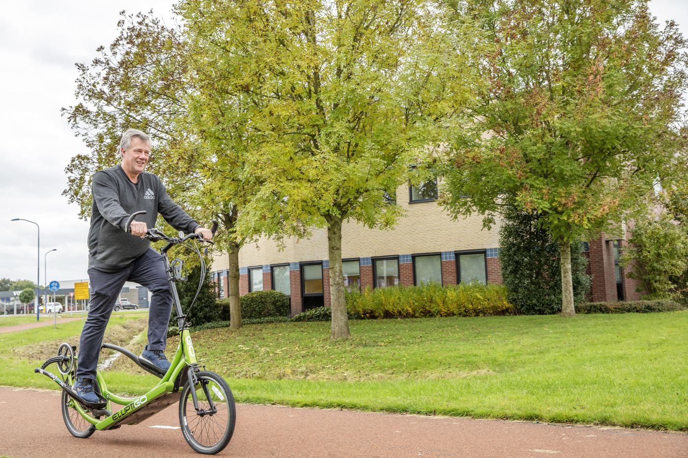Een man fietst op een stepfiets door het groen